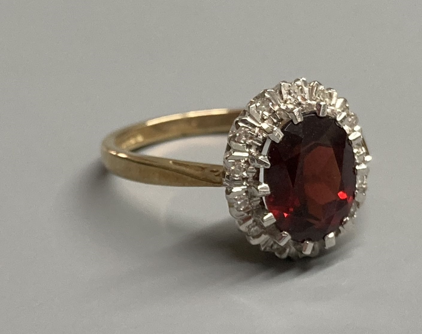 A modern 9ct gold, garnet and diamond set oval cluster ring, size N, gross 3.4 grams.